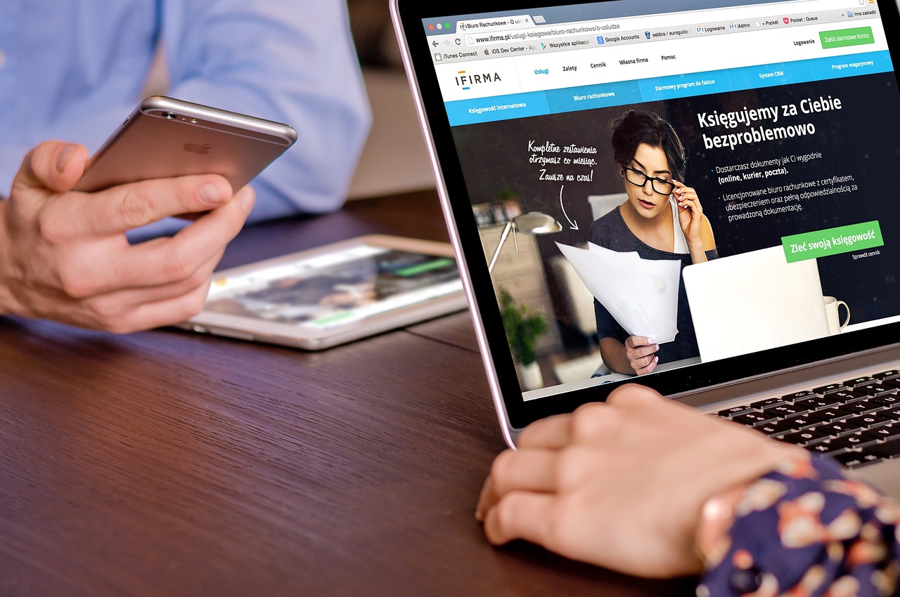 two BCW  marketers looking at a web design on a Macbook and iPhone.